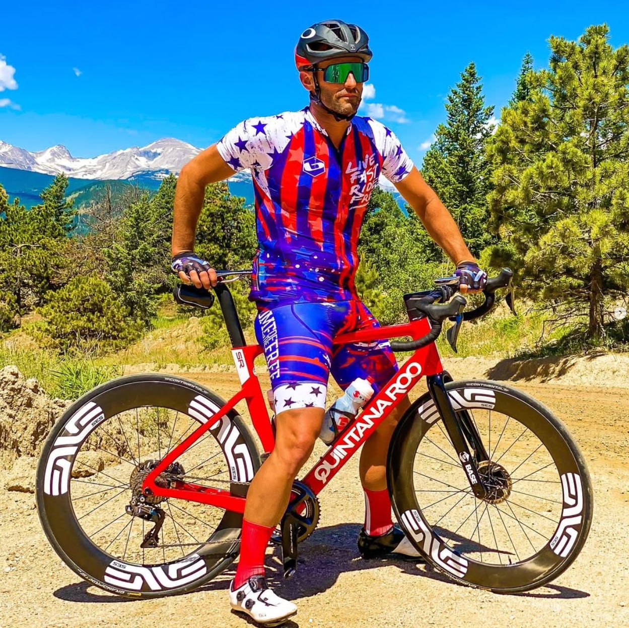Matt Miller standing with a red triathlon bike on a mountain road.