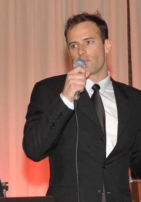 Matt Miller speaking into a microphone at a formal event.